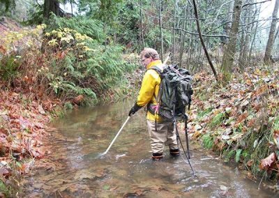 Biologist in waders sampling a forest stream