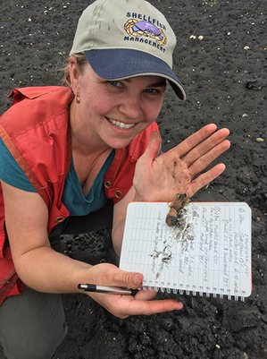 Biologist holding a shellfish sample on a field notebook during a beach survey