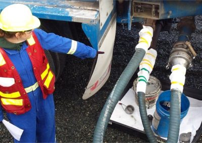 Monitor in a safety vest checking a fuel transfer hose