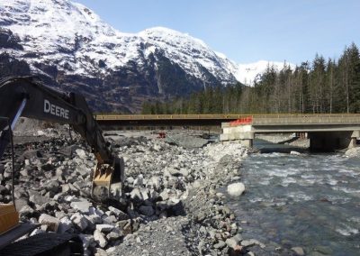 Excavator working beside Bitter Creek below snowy mountains