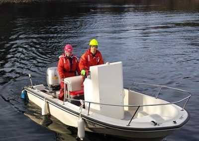 Two Aquaparian staff in survival suits on a small boat